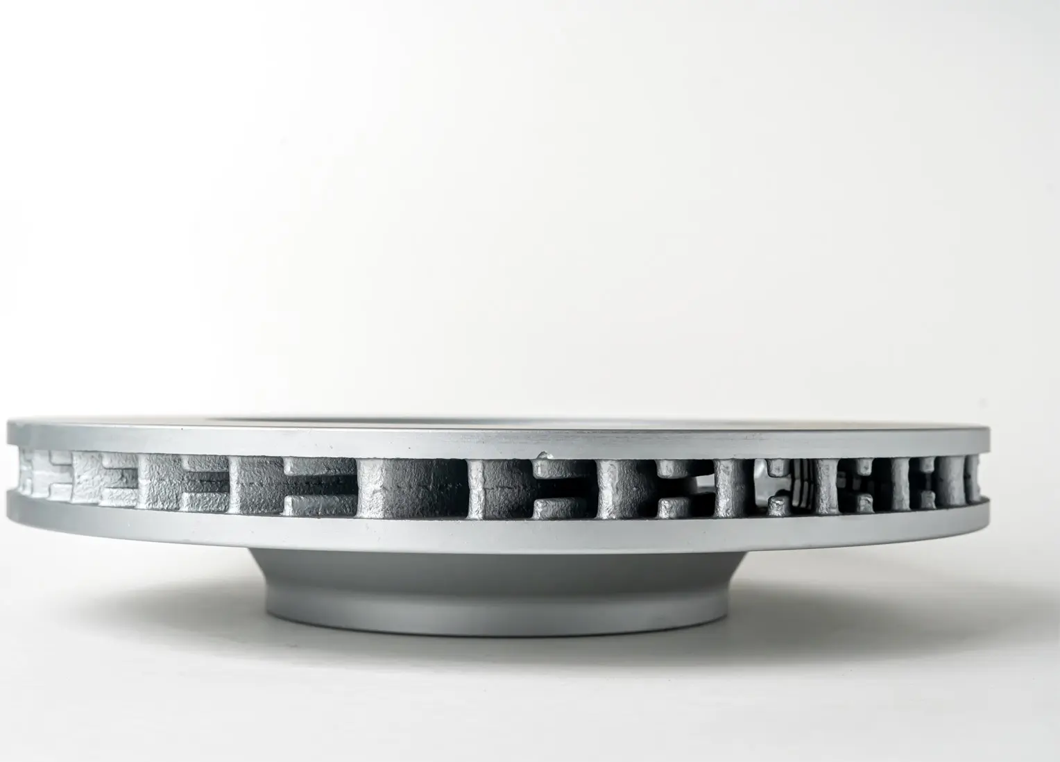 A side view of a vented brake disc showing the intricate internal structure and vents designed for cooling and improved performance.