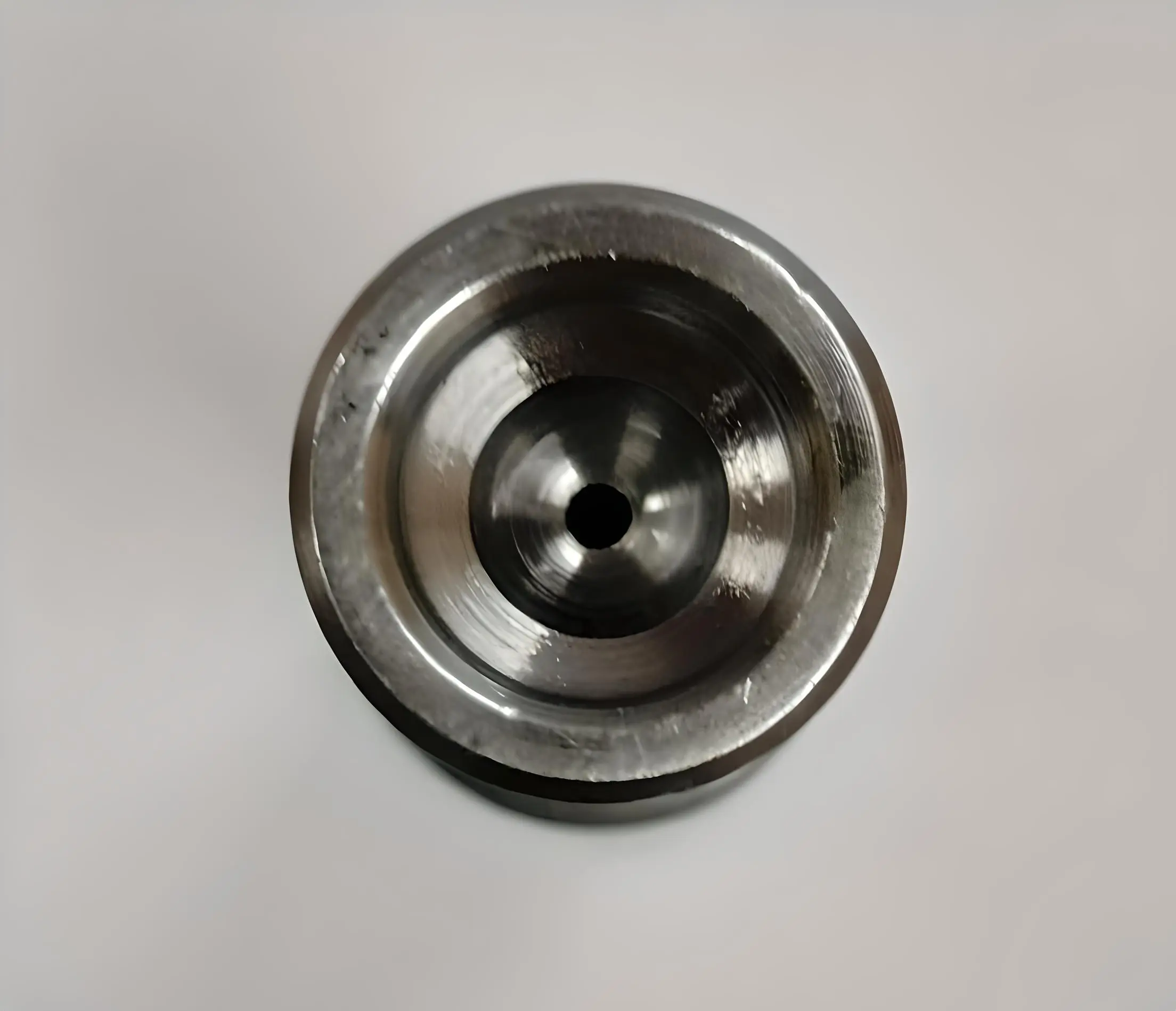 Top view of a cylindrical metal mushroom tappet with a central hole, displayed on a white background.