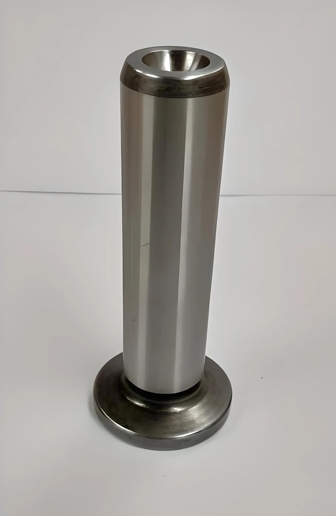 Front view of a cylindrical metal valve tappet with a concave top, displayed on a white background.