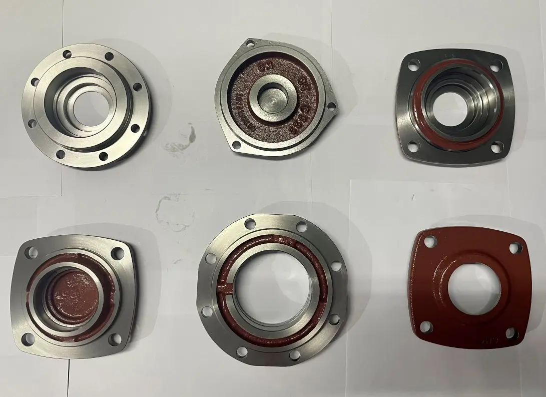 Six metal cover components with various shapes and bolt hole patterns, displayed on a white background.