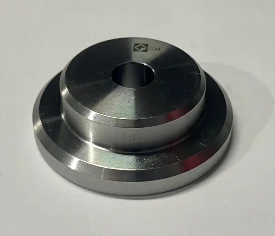 A metal flanged bush component with a circular hole in the center, displayed on a white background.