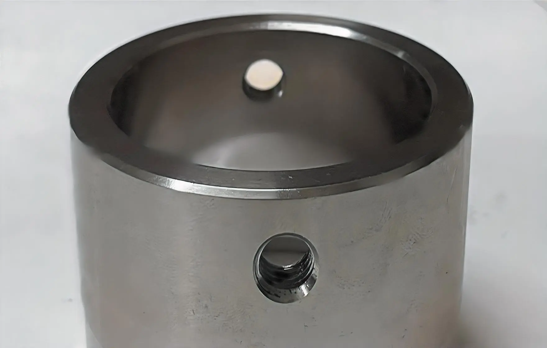 A cylindrical metal bush component with two circular holes, displayed on a white background.